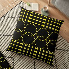 a black and yellow floor pillow with polka dots on it, next to a cup of coffee