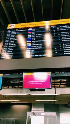 an airport check - in counter with a large screen displaying the flight times and destinations