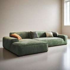 a green couch sitting in front of a window next to a white wall with two pillows on it