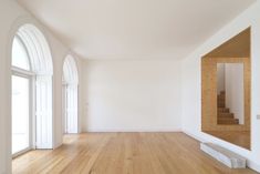 an empty room with wood flooring and arched doorways on either side of the wall