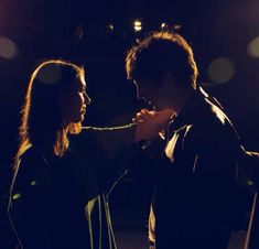 a man and woman standing next to each other in front of a dark room with lights