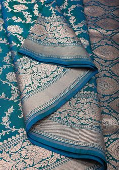 A Banarasi saree is a robust canvas where a weaver's unmatched craftsmanship, imagination, and creativity come to life! His dexterous hands beautifully blend the years of skills and experience to craft 6 yards of wearable art for the global woman of today's times. This saree is resplendent with all the elements of a rich Banarasi saree. The highlight of the drape is the intricately woven Floral jaal pattern on its rich body. The opulence of the drape is further enhanced by the traditional Banara Peacock Green Combination, Bridal Anklet, Trendy Outfits Indian, Bridal Makeup Images, Banarsi Saree, Katan Silk Saree, Peacock Pattern, Katan Silk, Banarasi Saree