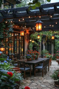 an outdoor dining area with potted plants and hanging lights on the ceiling, surrounded by stone pavers