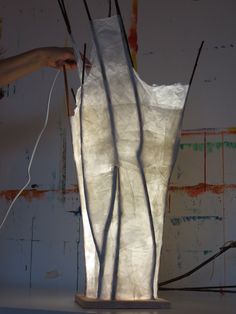 a person is working on a sculpture made out of white paper and wires with their hands