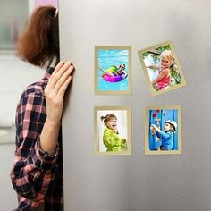 a woman looking at pictures on the side of a refrigerator that has magnets attached to it