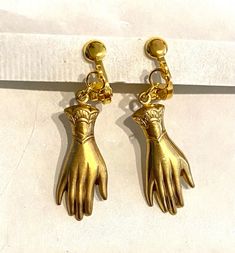 A pair of elegant hands two hand earrings created from two Victorian styled findings raw brass charms For non pierced ears with clip on fittings The hands hang from a loop at the front of the clip on fitting . When worn the bit that is visible is the circle at the front of the fitting  Raw brass has all the colour of 9ct gold without the price tag and can be polished with a good quality brass polish  I have not polished these as they are vintage findings Perhaps a present for an engagement or wedding with the emphasis on hands in both celebrations.  Please note that the hands are identical and therefore not a true 'pair' of hands.  These earrings hang from the cuffs , I have another version which hang from the fingers Also  mixed pairs with one hanging from the fingers, the other from the Brass Dangle Clip-on Earrings, Hand-cast Brass Dangle Earrings, Gold Hand Cast Dangle Earrings, Gold-tone Brass Clip-on Earrings, Brass Dangle Clip-on Earrings For Jewelry Making, Formal Dangle Brass Clip-on Earrings, Formal Brass Dangle Clip-on Earrings, Dangle Clip-on Wedding Earrings With Lever Back, Wedding Dangle Clip-on Earrings With Lever Back