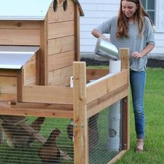 a woman pouring water into a bucket in her chicken coop