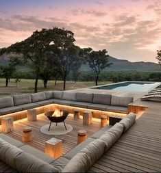 a large couch sitting on top of a wooden floor next to a swimming pool at sunset