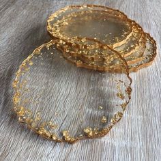 two pieces of gold colored glass sitting on top of a wooden table next to each other