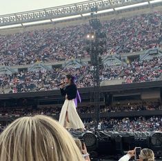 a woman standing on top of a stage in front of a crowd at a concert