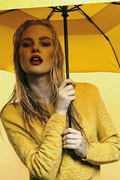 a woman holding an umbrella in front of her face and posing for the camera with red lipstick