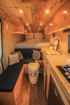 the interior of a small camper with wood flooring and walls, including a kitchen