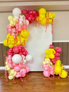 the balloon arch is decorated with pink, yellow and white balloons