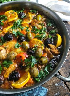 a pan filled with meat and vegetables on top of a wooden table