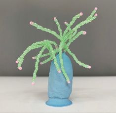 a blue vase filled with green and pink beads