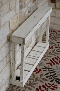 a white bench sitting on top of a rug next to a brick wall and floor