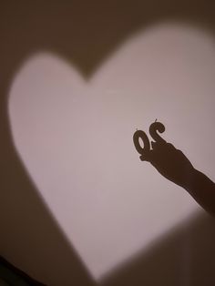 the shadow of a person's hand holding an object in the shape of a heart