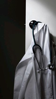 a stethoscope hanging from the side of a white coat on a wall