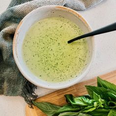 a bowl of broccoli soup on a cutting board next to a knife and napkin