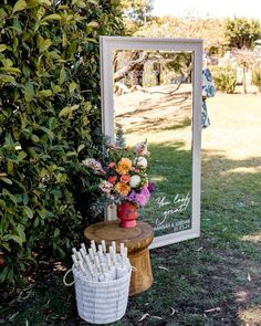 a mirror sitting on top of a wooden table next to a basket filled with flowers