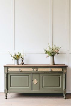 two potted plants sit on top of a green cabinet