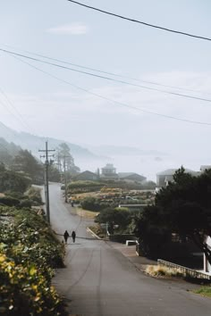 two people are walking down the road on a foggy day