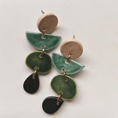 three pairs of green and brown earrings on a white surface