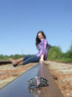 a woman sitting on the edge of a rail with her legs crossed in front of her