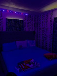 a bed in a room lit up with purple light and pillows on the bottom side