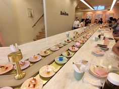 a long table with many plates on it and people sitting at the tables in the background