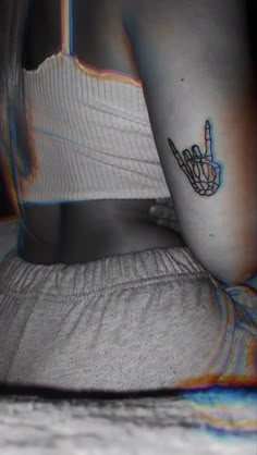 a person with a tattoo on their arm and hand pointing to the left, while sitting down