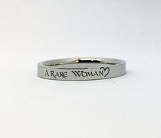 "This line of stainless steel rings (sizes 5-11) is engraved with \"A Rare Woman\" in a celtic font with a half heart design on one end. The ring is laser engraved permanently in black on the surface of the ring. --Choose from Silver, Gold, Rose Gold (all with black engraving) or Black- with silver engraving. --Rings come in a small gift box. This style stainless steel ring is 3mm wide - thin enough to wear multiples. PLEASE be sure of your ring size before ordering. If you're interested in your Engraving Rings, Celtic Fonts, Celtic Heart Knot, Half Heart, Ring Spacer, Name Rings, Small Gift Boxes, Silver Engraving, Engraved Jewelry