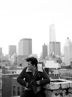 a man sitting on top of a building next to a fire hydrant in front of a city skyline