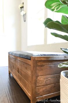 a wooden bench sitting on top of a hard wood floor next to a potted plant