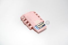 a small pink purse with money sticking out of it's side on a white surface