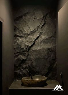 a bathroom with stone walls and a round sink in the middle, surrounded by dark lighting