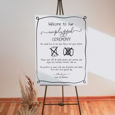 a welcome sign on an easel in front of a white wall and wooden floor