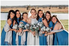 a group of women standing next to each other in front of a body of water