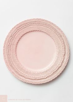 pink plates stacked on top of each other in the shape of lacy doily, against a white background