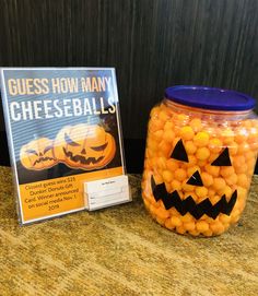 a glass jar filled with candy sitting next to a sign that says guess how many cheese balls are in it