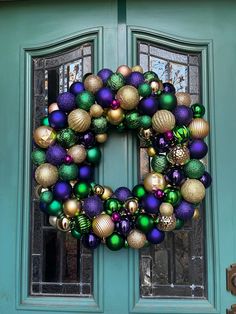 a christmas wreath on the front door of a house with ornaments hanging from it's side