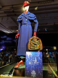 a woman's blue dress and red shoes on display in front of a crowd