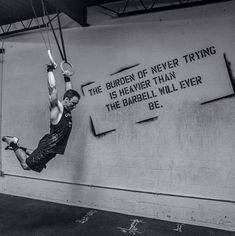 a man hanging upside down on a rope in front of a wall with words painted on it