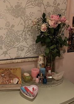 a vase filled with pink roses sitting on top of a table next to a mirror