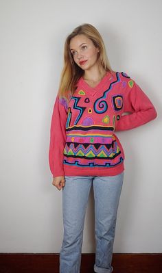 "What a fun funky bright sweater! Definitely a statement piece- bright pink and a great silhouette then the crazy print. The print is upraised and textured making it even cooler. This is tagged an xs but feel it too be closer to a modern medium. There are no flaws to note, in great shape. Measurements are taken flat and doubled where needed. Pit to pit: Waist: Length: Sleeves: Model is 5'5\" and usually a small for reference. Dopey Dog Vintage is a resale shop. While my dog Bandit is present in my home, items are stored away from him. If an allergy is a concern and you are interested in an item- please reach out as I would be happy to work with you. All of the items sold have been worn/used, I aim to pick out items in good to excellent condition and aim to be transparent about any flaws or Fun Multicolor Spring Sweater, Pink Long Sleeve Sweater With Graphic Print, Casual Pink Sweater With Graphic Print, Colorful Trendy Winter Tops, Trendy Colorful Winter Tops, Playful Pink Crew Neck Sweater, Trendy Multicolor Sweater With Graphic Print, Playful Fitted Winter Sweater, Playful Fitted Sweater For Winter