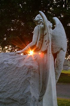 an angel statue with the sun setting behind it