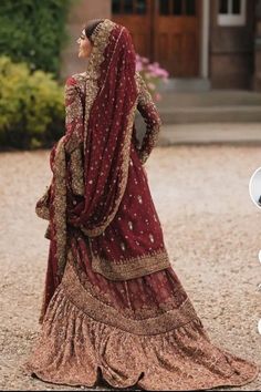 a woman in a red and gold bridal gown is looking at something on the ground