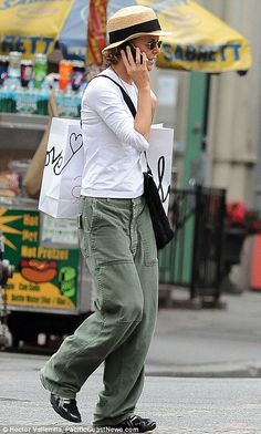 a woman is walking down the street talking on her cell phone and holding a bag