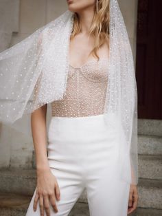 a woman in white pants and a veil on her head