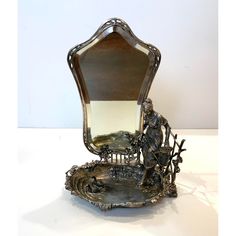 an ornate silver mirror sitting on top of a table